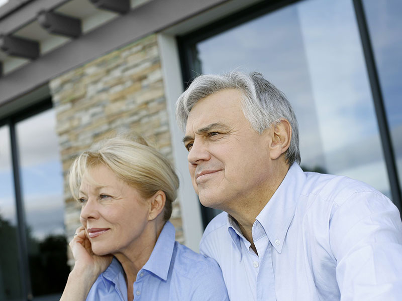 Couple de retraités devant leur maison.