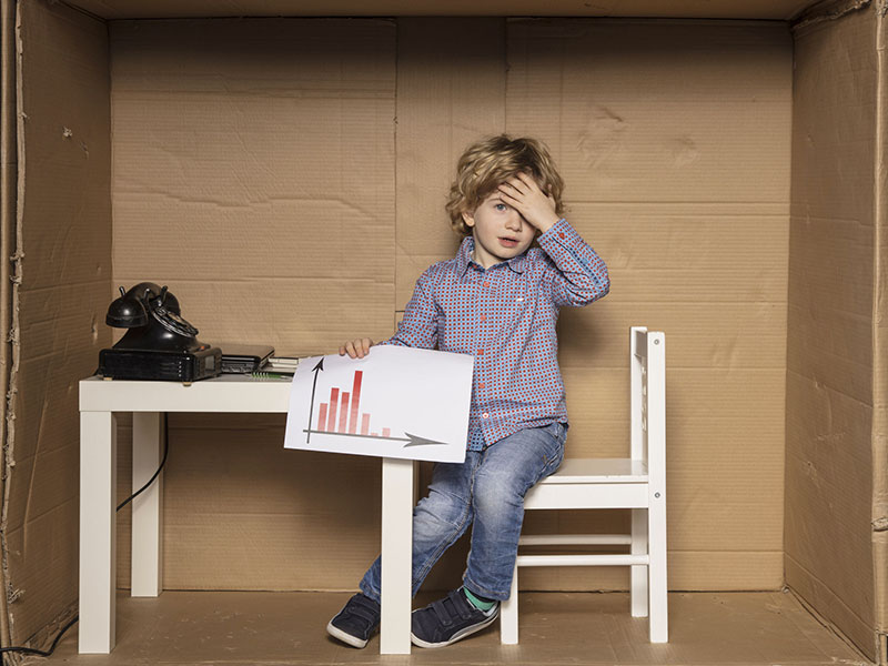 Enfant l'air découragé, tenant une feuille contenant un graphique économique.