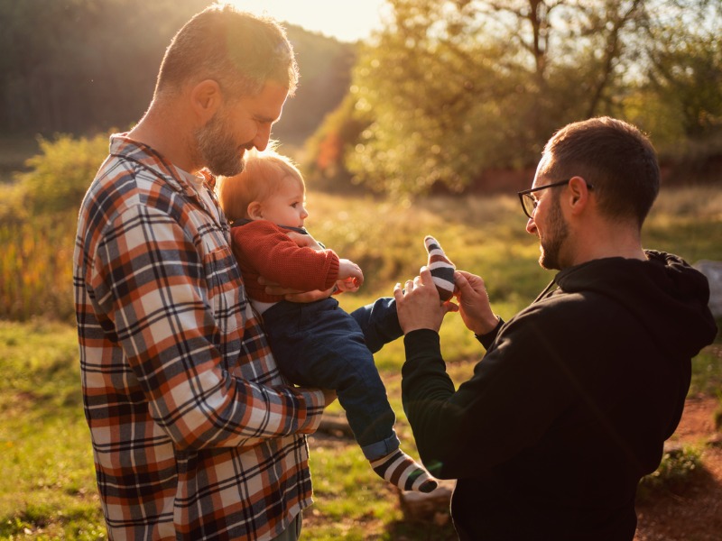 Un couple d'hommes avec un petit garçon dans la campagne.