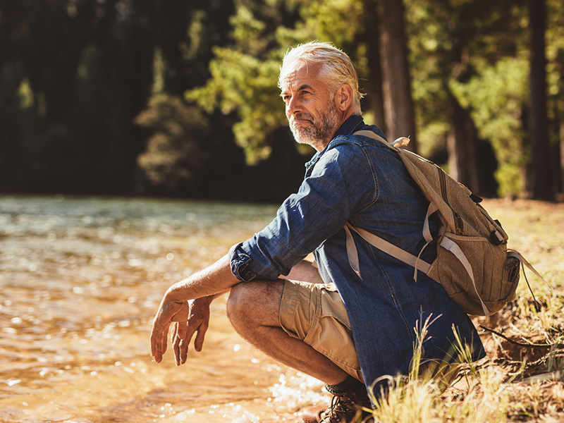 Homme retraité devant un lac.