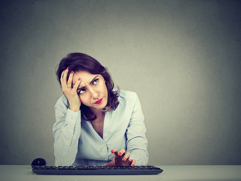 Femme désespérée devant le clavier de son ordinateur.