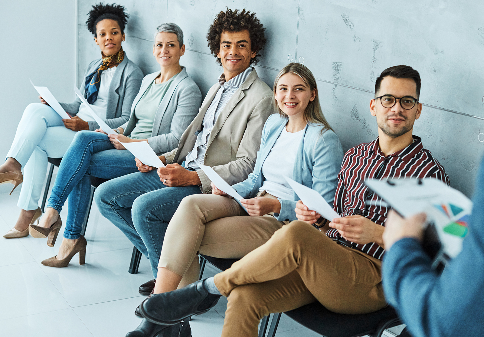 Groupe de jeunes hommes d'affaires assis sur des chaises et attendant un entretien