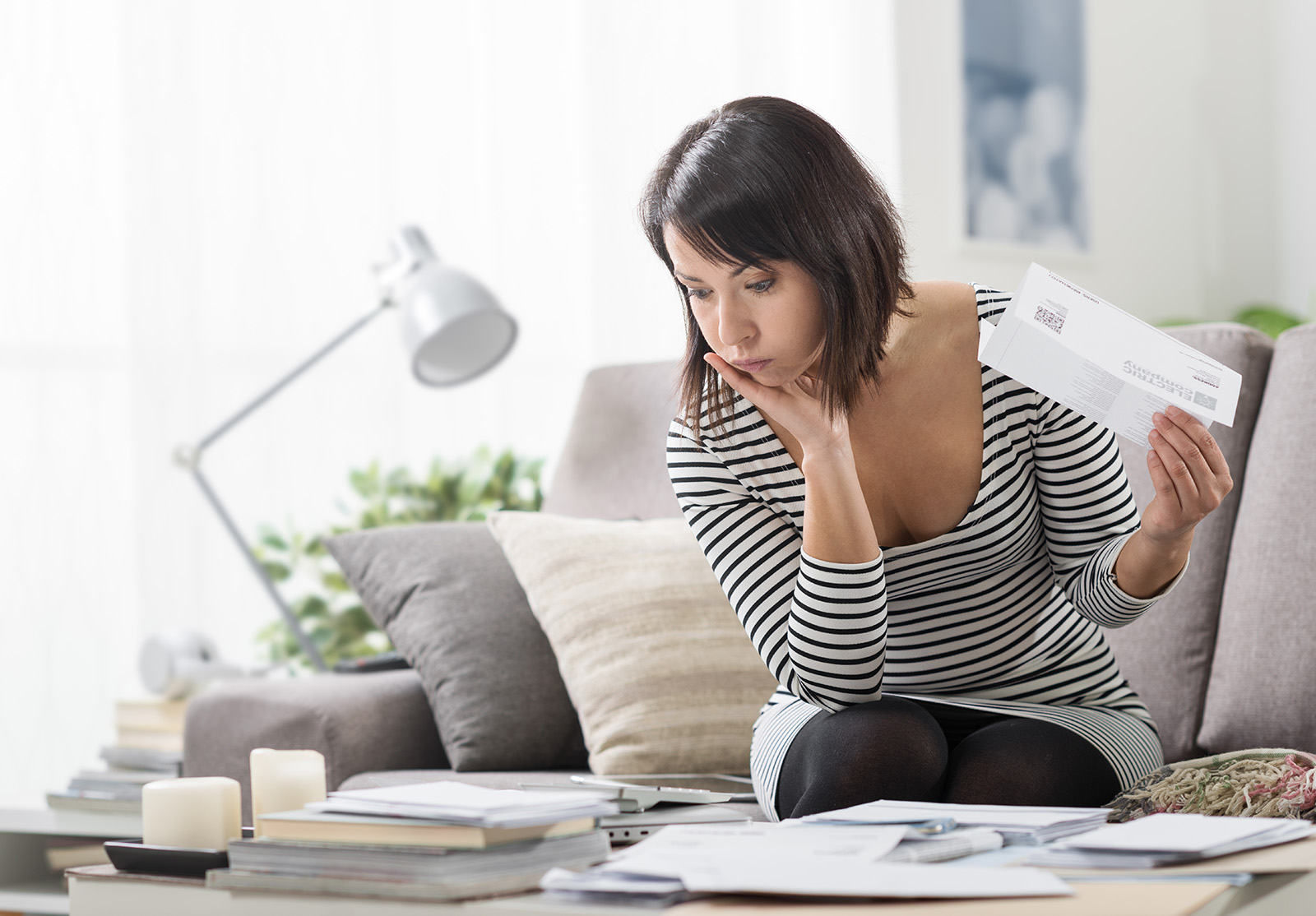 Femme stressée à la maison, vérifiant des factures d'électricité et de ménage onéreuses, concept de finance domestique