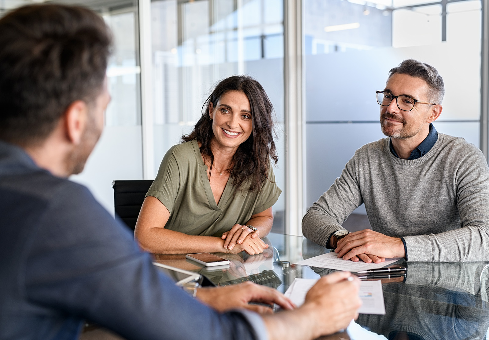 Couple d'âge mûr souriant rencontrant un directeur de banque pour un investissement. Belle femme d'âge mûr et son mari écoutant un homme d'affaires lors d'une réunion dans la salle de conférence d'un bureau moderne. Couple heureux d'âge moyen rencontrant un conseiller en prêts pour l'achat d'une nouvelle maison.