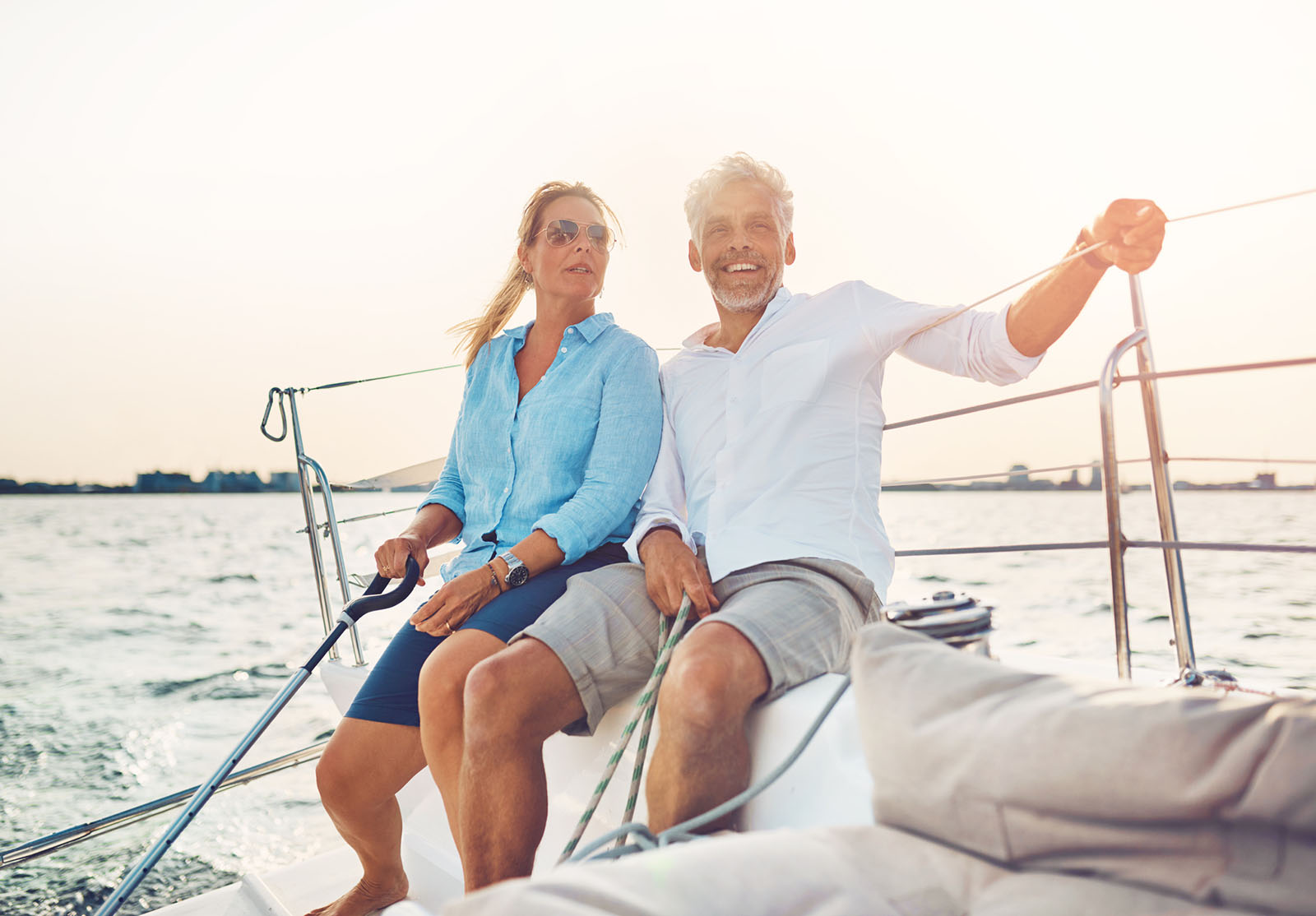 Couple souriant assis sur le pont de leur bateau, profitant d'une journée de navigation par un après-midi ensoleillé.