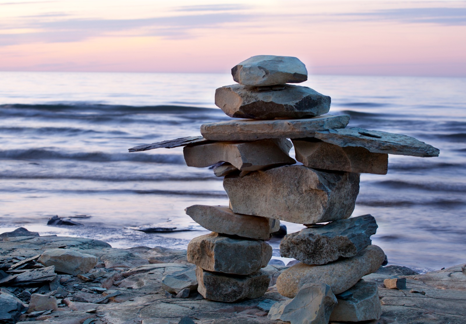 Inuksuk au coucher du soleil sur une plage.