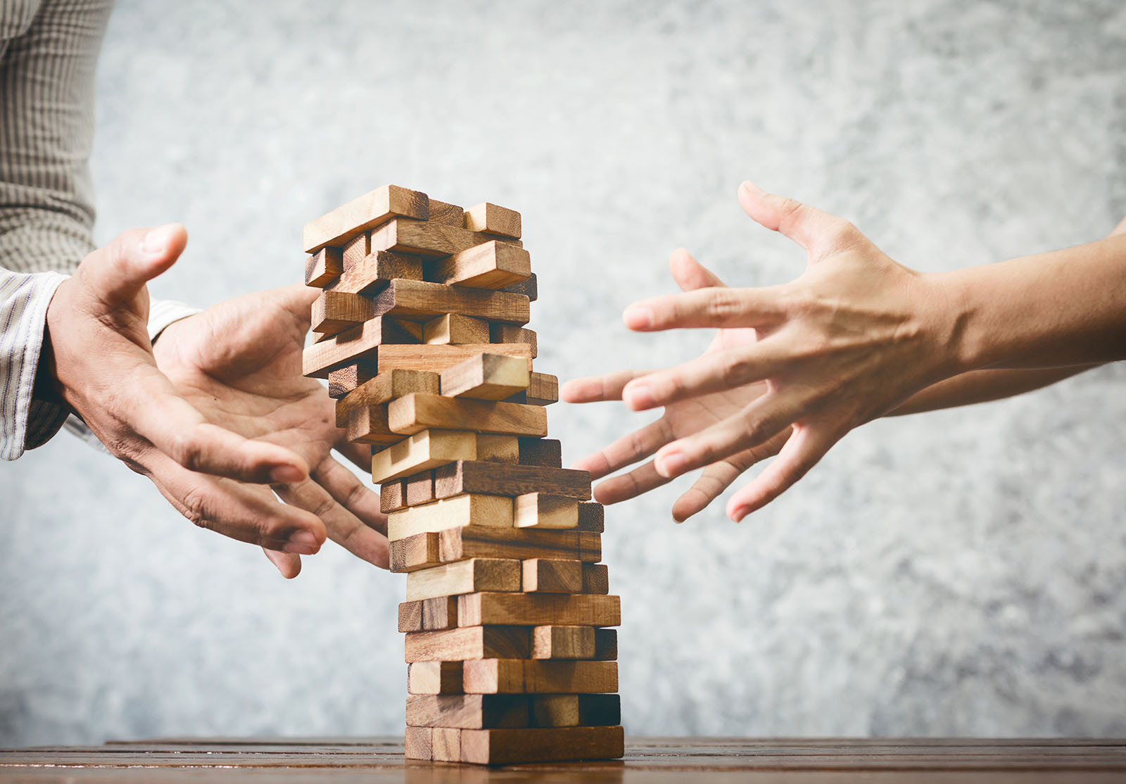 Homme et femme d'affaires jouant au jeu de jenga en bois dans un bureau.